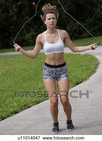 Stock Photo - Young woman exercising with jump rope. Fotosearch