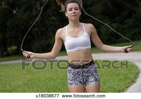 Stock Photo - Young woman exercising with jump rope. Fotosearch