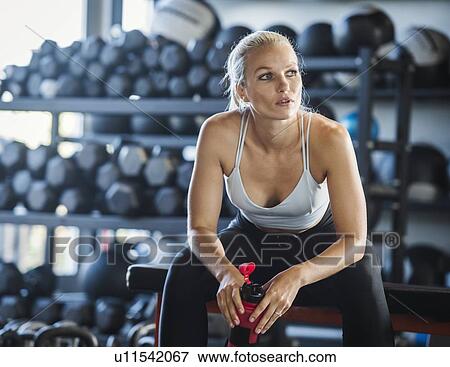 Young woman holding bottle in gym View Large Photo Image Stock Photo - Young woman holding bottle in gym. Fotosearch