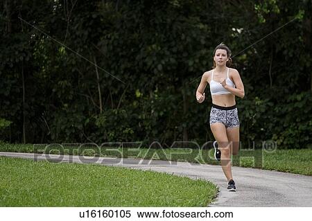 Stock Photography - Young woman jogging in park. Fotosearch
