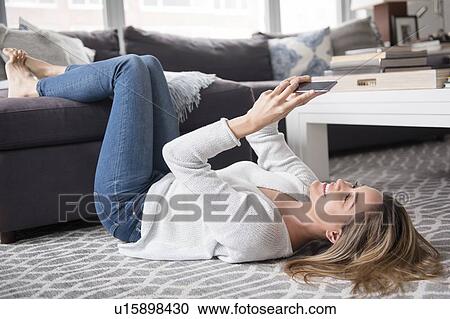 Young woman lying on back and using smart phone View Large Photo Image Stock Image - Young woman lying on back and using smart phone. Fotosearch
