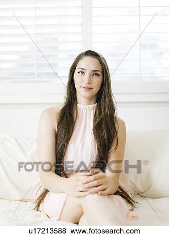 Stock Photo - Young woman sitting on bed. Fotosearch