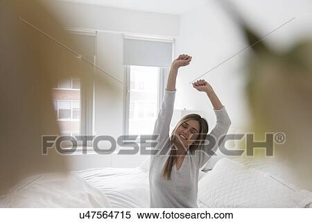 Stock Photography - Young woman stretching in bedroom. Fotosearch