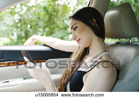 Young woman using smart phone in car View Large Photo Image Picture - Young woman using smart phone in car. Fotosearch