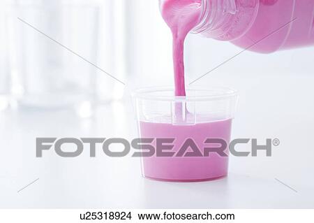 Picture - Antacid medicine being poured into a dosing cup.. Fotosearch