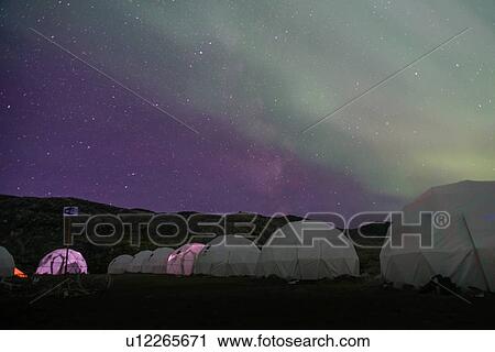 Stock Image - Aurora borealis over row of dome tents, Narsaq, Vestgronland, Greenland. Fotosearch