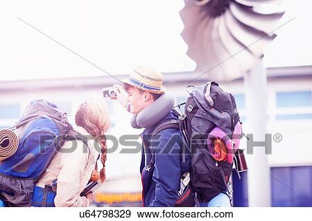 Stock Photo - Backpacker couple taking selfie at airport. Fotosearch