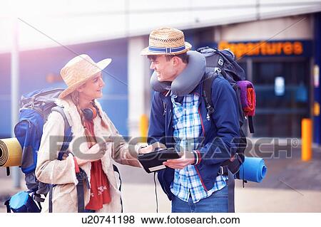 Stock Photo - Backpacker couple using digital tablet at airport. Fotosearch