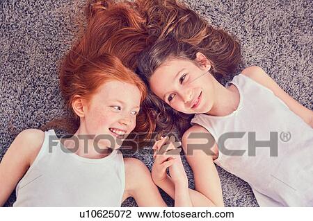 Stock Image - Best friends holding hands on carpet. Fotosearch