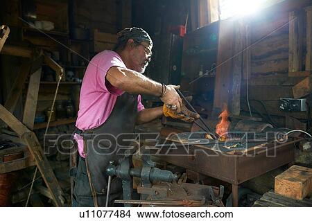 Picture - Blacksmith working in his forge. Fotosearch