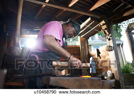 Blacksmith working in his forge View Large Photo Image Stock Image - Blacksmith working in his forge. Fotosearch