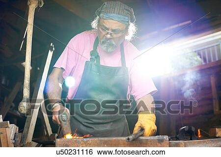 Stock Photograph - Blacksmith working in his forge. Fotosearch