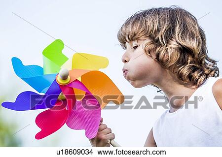 Boy blowing colourful paper windmill in park. View Large Photo Image Picture - Boy blowing colourful paper windmill in park.. Fotosearch