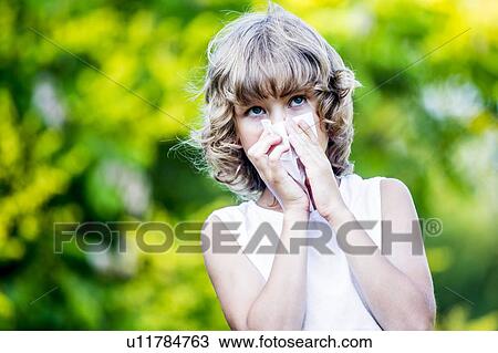 Stock Image - Boy blowing his nose in park.. Fotosearch