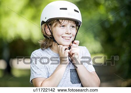 Boy fastening bicycle helmet in park, smiling. View Large Photo Image Stock Image - Boy fastening bicycle helmet in park, smiling.. Fotosearch
