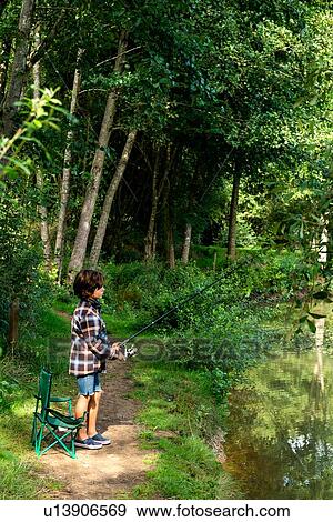 Stock Photo - Boy fishing by lakeside, Bournemouth, UK. Fotosearch