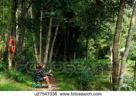 Stock Photograph - Boy fishing by lakeside, Bournemouth, UK. Fotosearch