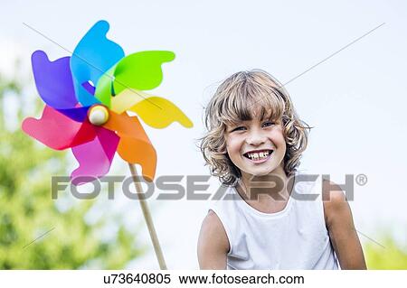 Stock Photography - Boy holding paper windmill, smiling.. Fotosearch