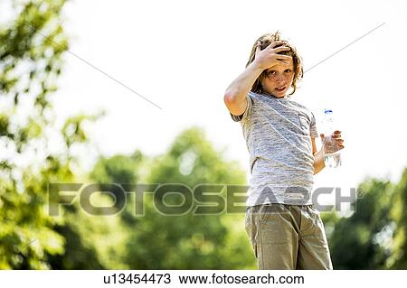 Boy holding water bottle in park, portrait. View Large Photo Image Stock Image - Boy holding water bottle in park, portrait.. Fotosearch