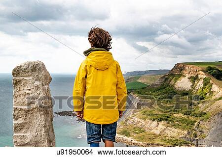 Picture - Boy on clifftop looking out to sea, Bournemouth, UK. Fotosearch