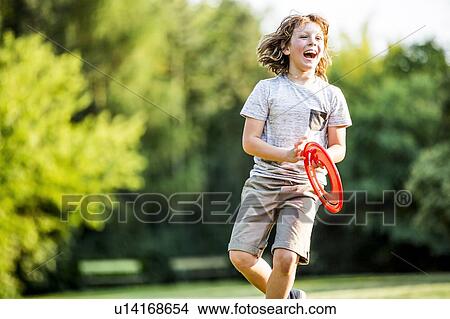 Picture - Boy playing with flying disc in park, laughing.. Fotosearch