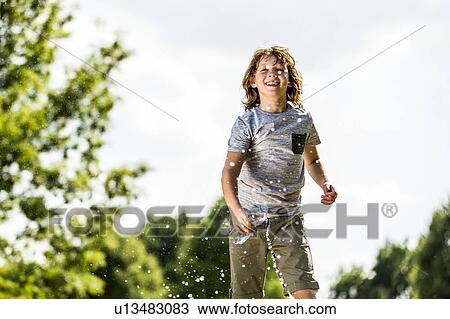 Boy splashing water from plastic bottle, smiling, portrait. View Large Photo Image Stock Image - Boy splashing water from plastic bottle, smiling, portrait.. Fotosearch