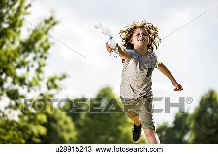 Boy splashing water from plastic bottle, smiling, portrait. View Large Photo Image Stock Image - Boy splashing water from plastic bottle, smiling, portrait.. Fotosearch