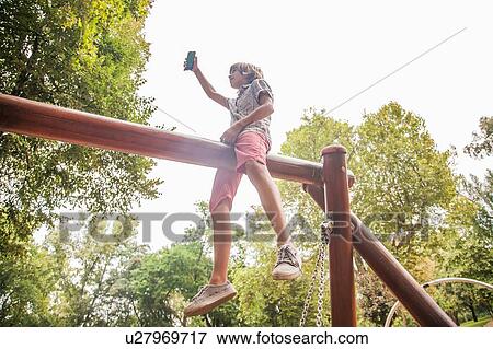Boy taking selfie on playground equipment View Large Photo Image Stock Photo - Boy taking selfie on playground equipment. Fotosearch