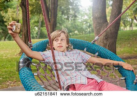 Boy taking selfie on web swing View Large Photo Image Stock Image - Boy taking selfie on web swing. Fotosearch