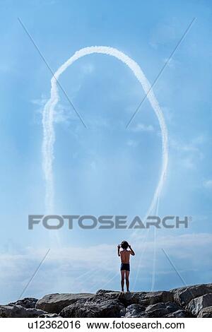 Boy watching aerobatics demonstration from rocky beach View Large Photo Image Stock Photograph - Boy watching aerobatics demonstration from rocky beach. Fotosearch