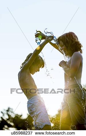 Boys pouring water on each other from plastic bottle, laughing. View Large Photo Image Stock Photo - Boys pouring water on each other from plastic bottle, laughing.. Fotosearch