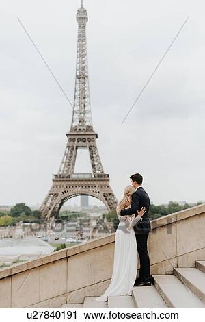 Stock Image - Bride and bridegroom, Eiffel Tower in background, Paris, France. Fotosearch