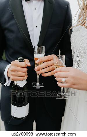 Bride and bridegroom holding champagne bottle and flutes View Large Photo Image Stock Photo - Bride and bridegroom holding champagne bottle and flutes. Fotosearch
