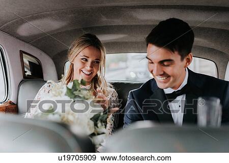 Stock Photo - Bride and bridegroom in backseat of car. Fotosearch