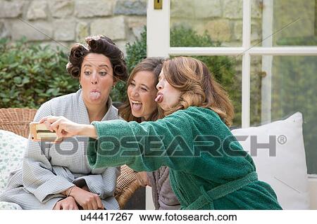 Bride and friends taking selfie on morning of wedding day View Large Photo Image Stock Photo - Bride and friends taking selfie on morning of wedding day. Fotosearch