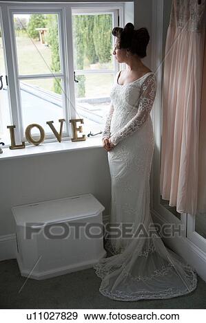 Bride looking out of window before wedding View Large Photo Image Stock Photo - Bride looking out of window before wedding. Fotosearch