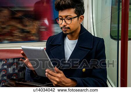 Stock Image - Businessman using digital tablet inside train. Fotosearch