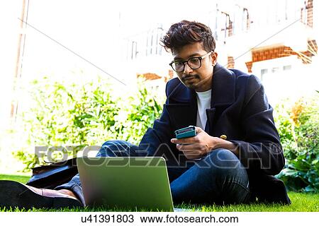 Businessman using smartphone and laptop on grass View Large Photo Image Stock Image - Businessman using smartphone and laptop on grass. Fotosearch