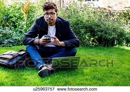 Businessman using smartphone and laptop on grass View Large Photo Image Stock Photo - Businessman using smartphone and laptop on grass. Fotosearch