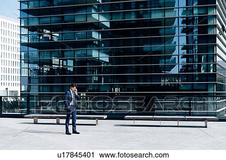 Businessman using smartphone in front of office building View Large Photo Image Stock Image - Businessman using smartphone in front of office building. Fotosearch