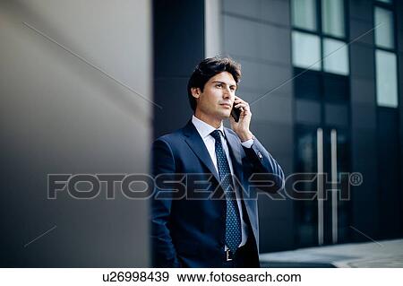 Businessman using smartphone in front of office building View Large Photo Image Stock Photo - Businessman using smartphone in front of office building. Fotosearch