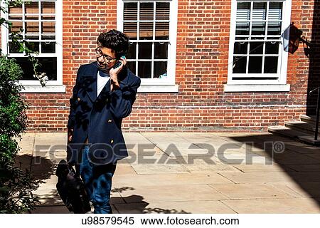 Stock Photography - Businessman using smartphone in front of building. Fotosearch