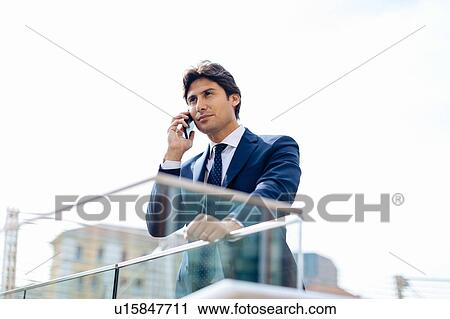 Stock Image - Businessman using smartphone on terrace. Fotosearch