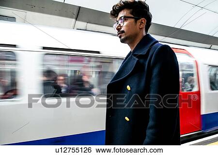 Stock Photograph - Businessman waiting on platform of subway station, London, UK. Fotosearch