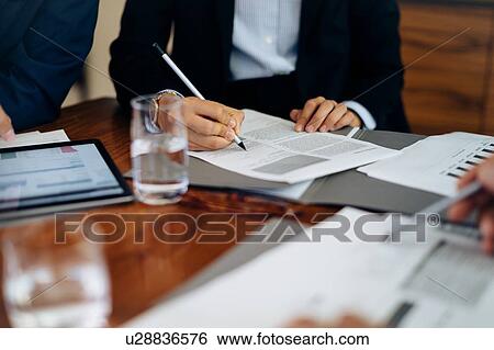 Businessmen and woman at boardroom table working on paperwork, cropped View Large Photo Image Stock Photograph - Businessmen and woman at boardroom table working on paperwork, cropped. Fotosearch