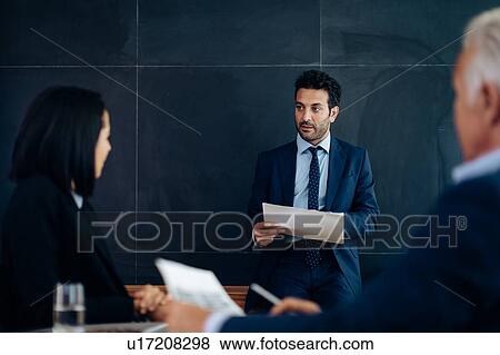 Stock Photo - Businessmen and woman meeting in boardroom. Fotosearch
