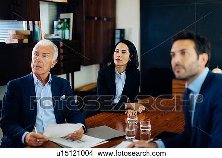 Picture - Businessmen and woman watching presentation from boardroom table. Fotosearch