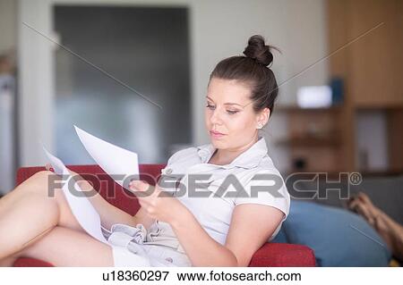 Stock Photo - Businesswoman reading documents on sofa. Fotosearch