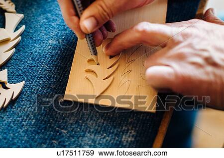 Stock Photo - Carpenter drawing outline of wooden christmas tree, close up of hands. Fotosearch