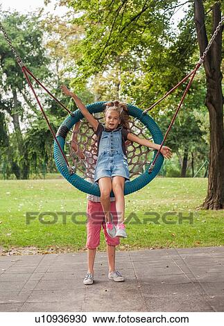 Child pushing girl on web swing View Large Photo Image Stock Image - Child pushing girl on web swing. Fotosearch